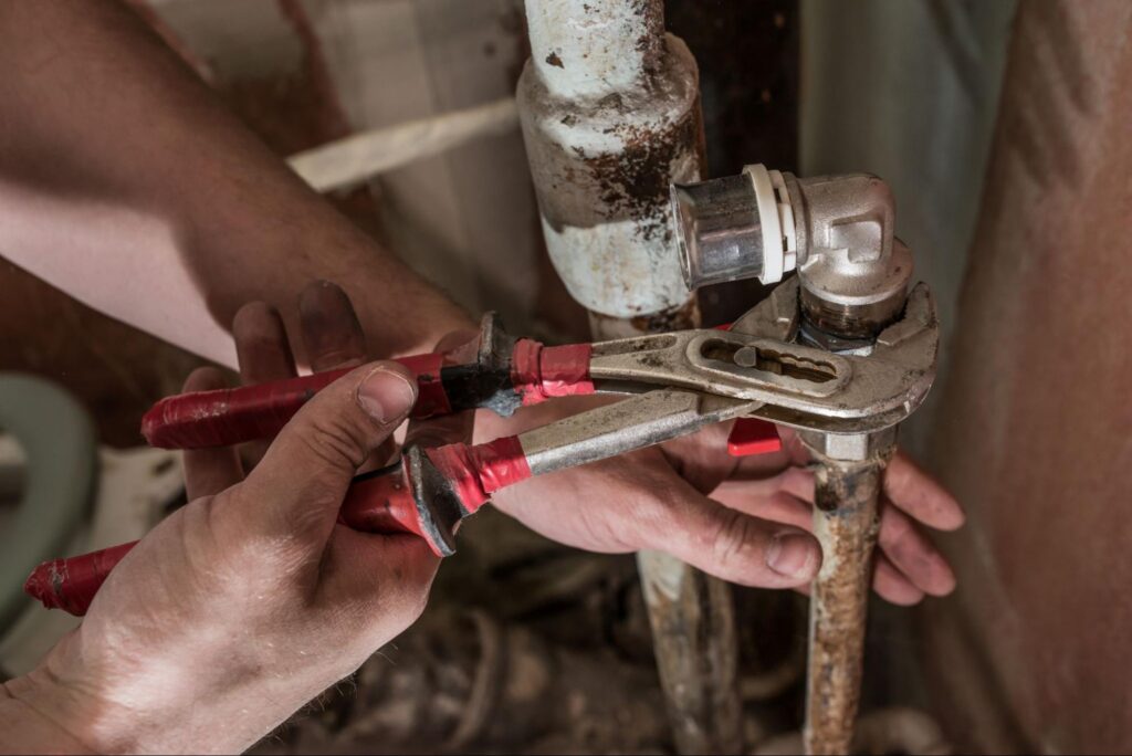 plumber repairing corroded pipes in an older home during plumbing system evaluation
