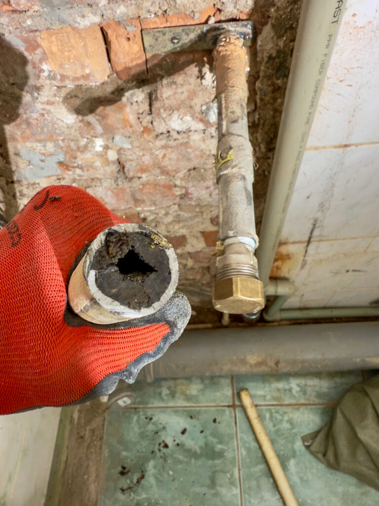 severely corroded pipe with mineral buildup removed during plumbing inspection in older home