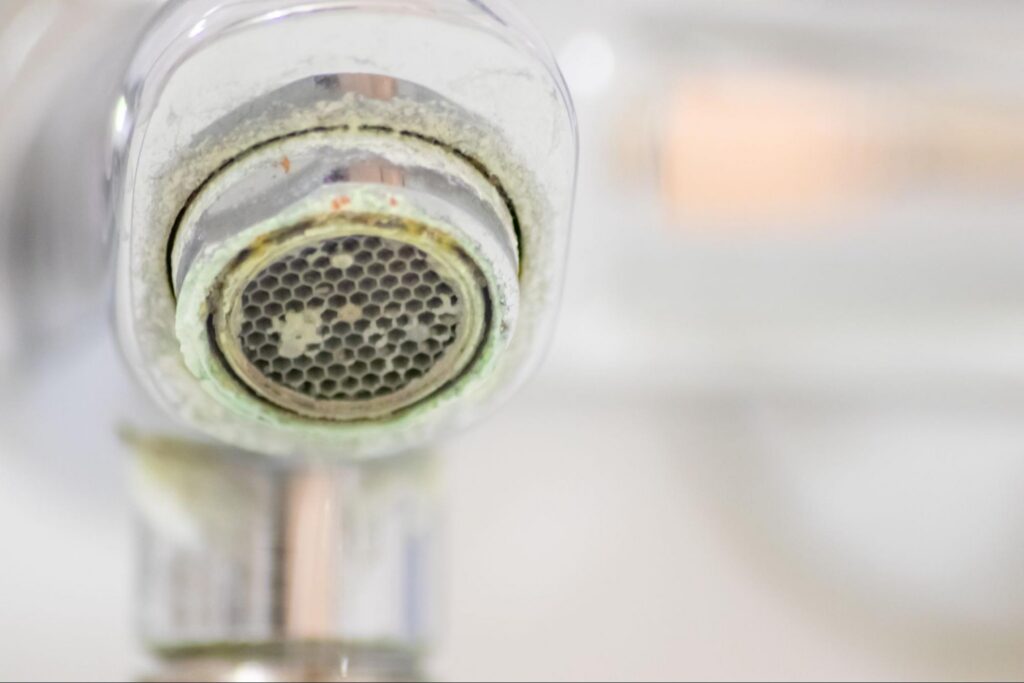 Limescale buildup on a faucet aerator, a common sign of hard water damage A&N Plumbing addresses in homes.