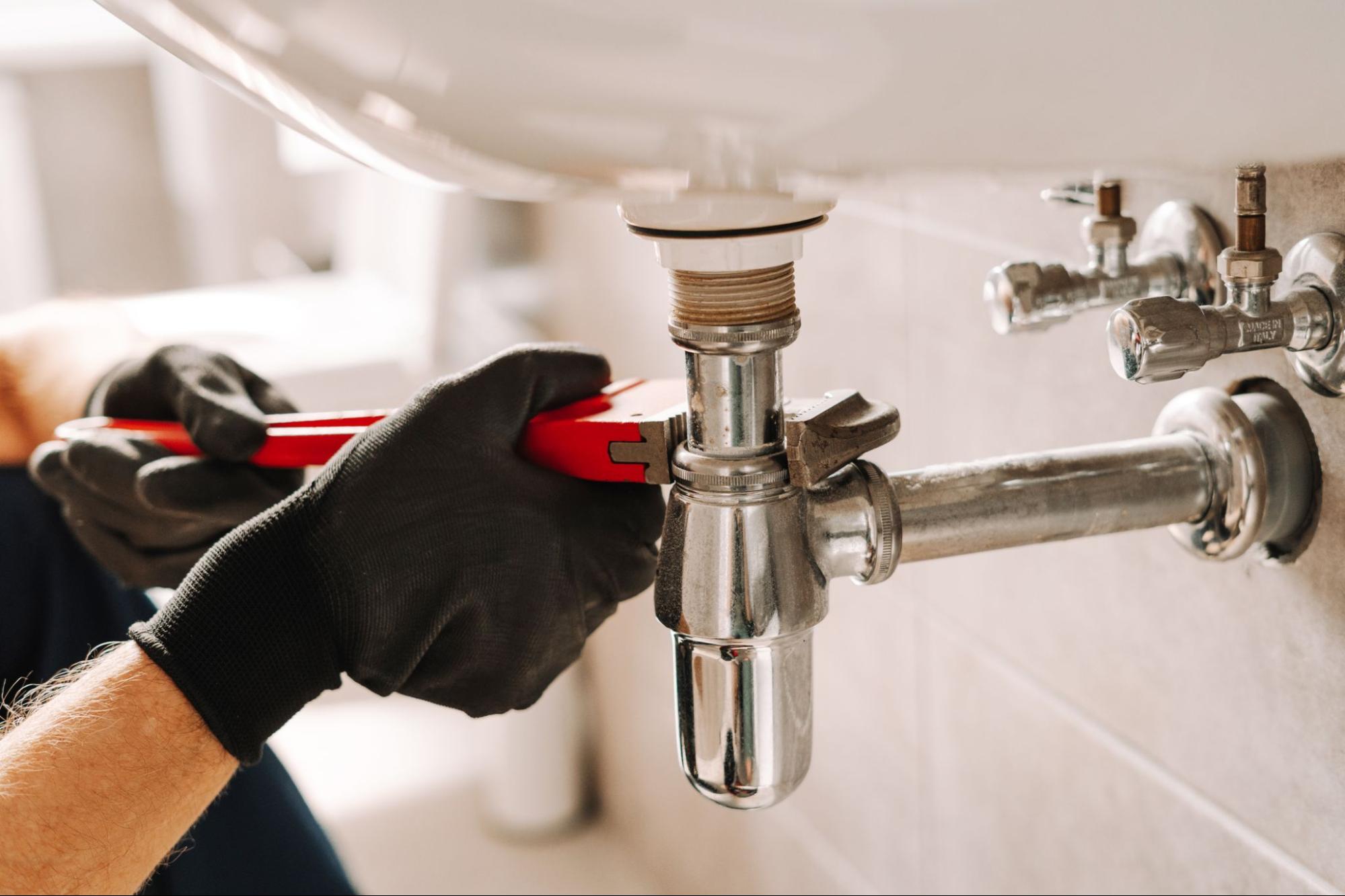 A plumber repairing a home sink drain line during a plumbing repair in Wenatchee, WA.