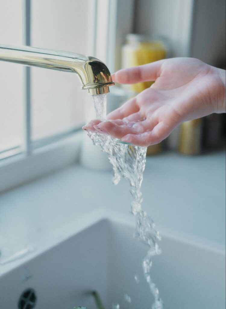 Clean water flowing from a kitchen faucet, the consistent water quality homeowners aim for when addressing signs of hard water damage.