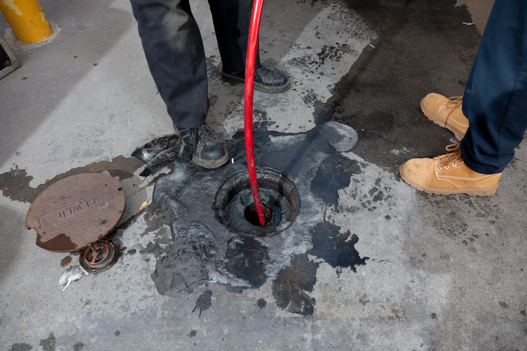A plumber performs hydro jetting in Wenatchee, WA, feeding a jetting hose into a drain cleanout.