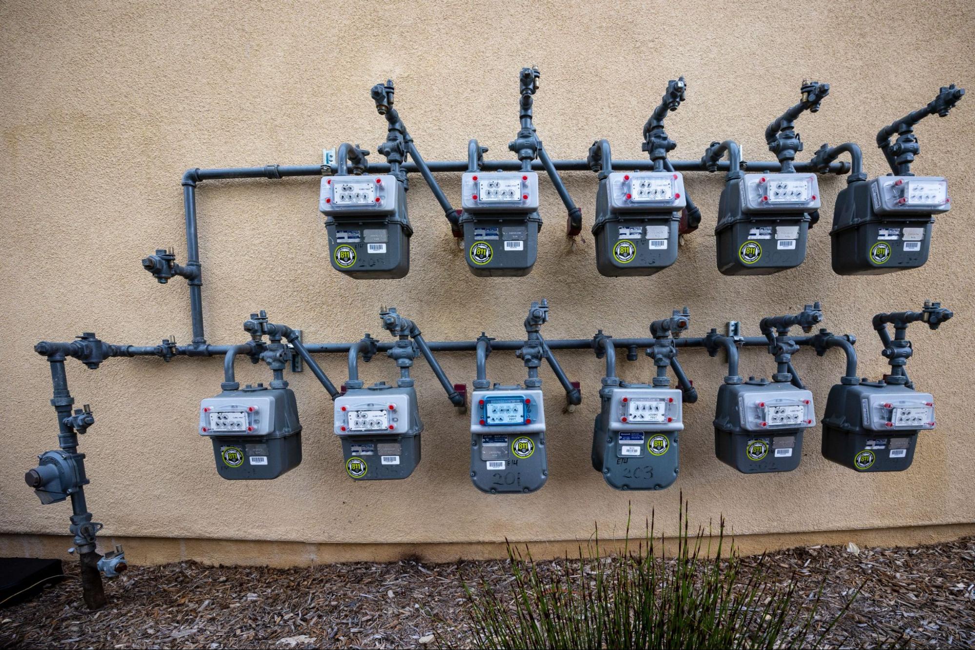 Natural gas meters and lines mounted on a stucco wall in Scottsdale, AZ.