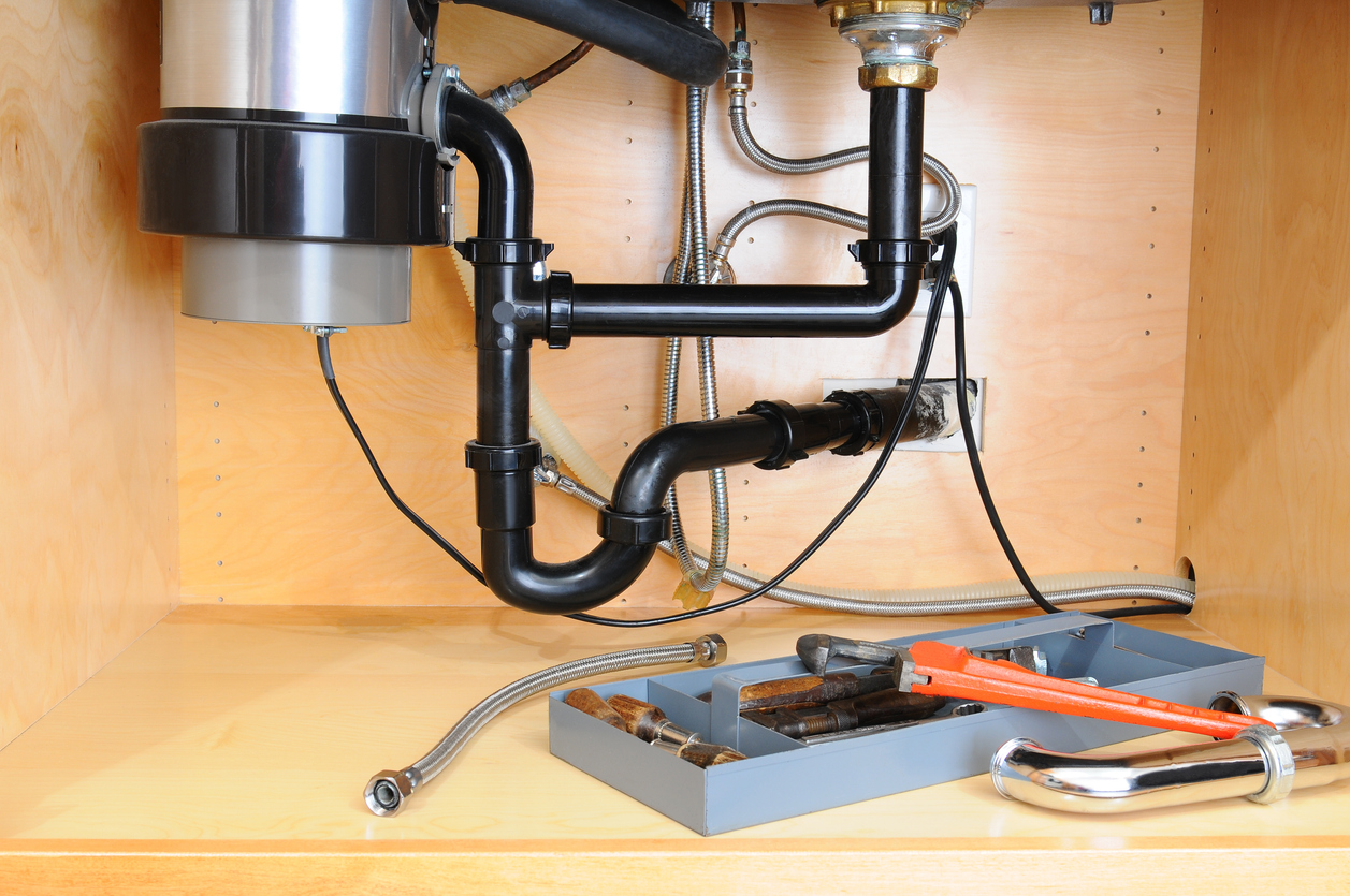 Under-sink plumbing showing the curved P-trap, supply lines, and drain connections.