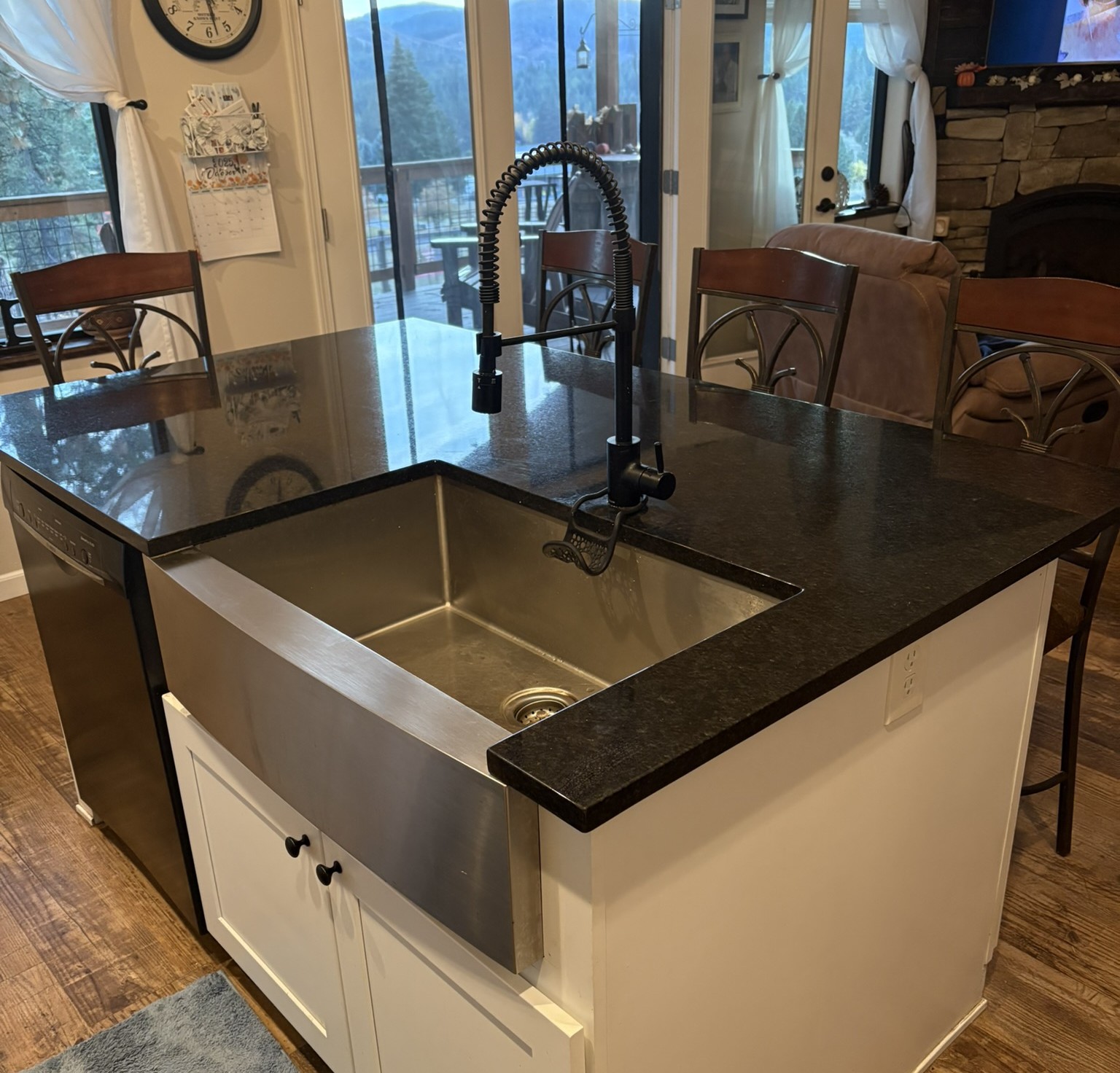A stainless steel farmhouse sink and black pull-down faucet after a kitchen fixture installation.