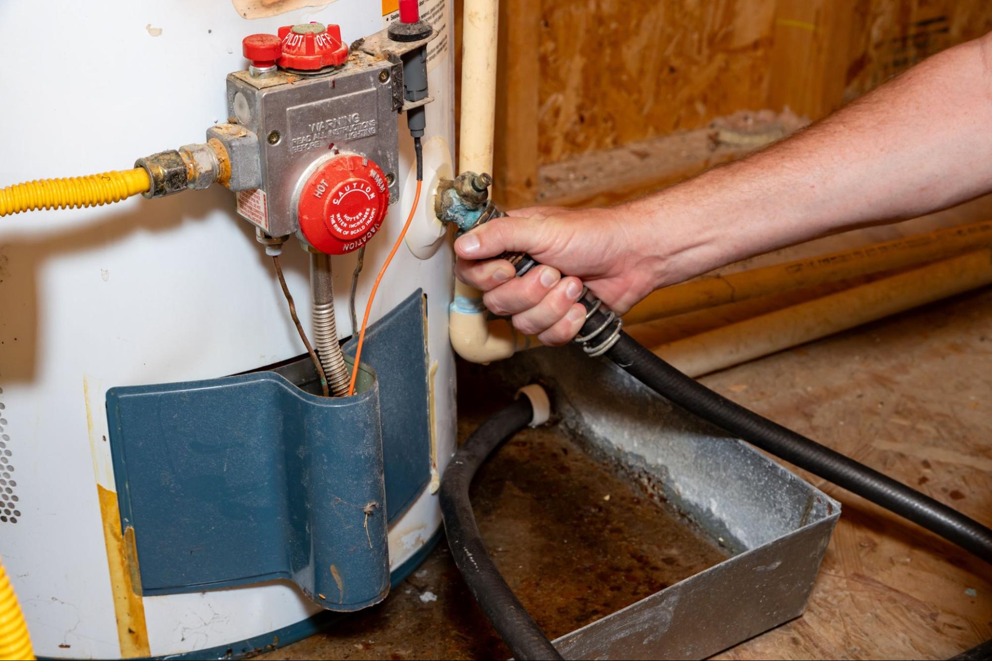 A plumber connects a drain hose to flush sediment from a water heater in East Wenatchee, WA.